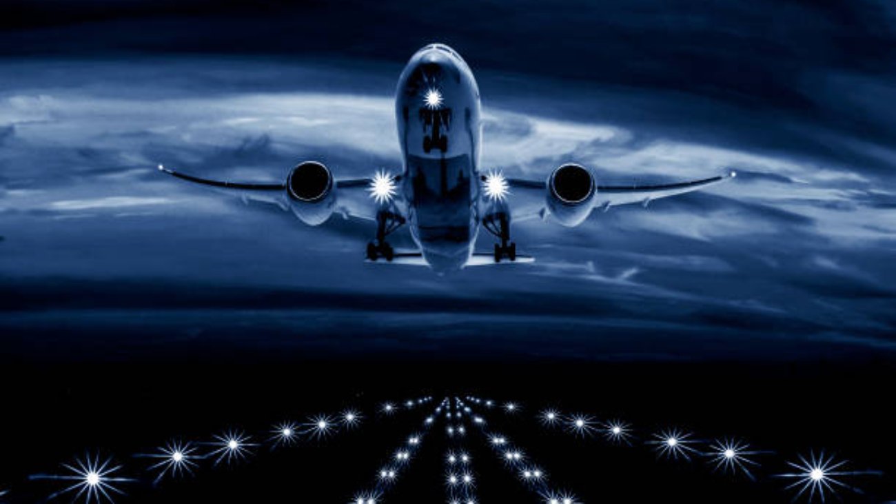 A passenger plane takes off from the night airport runway