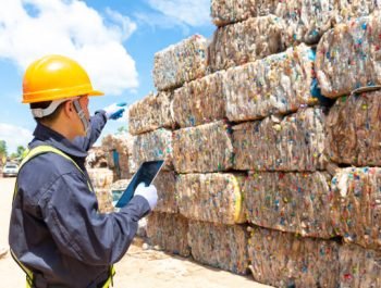 An employee at a recycling plant is pointing to plastic waste being sent to the recycling process. Engineer looking and pointing forward.